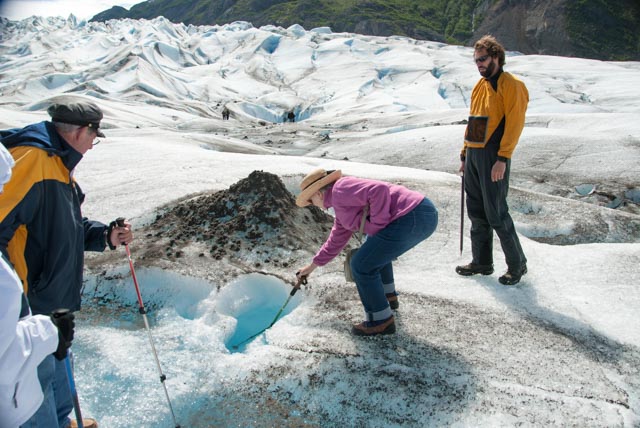Marilyn explores a hole in the ice with her walking pole. Some of the holes disappear far into the depths of the glacier.