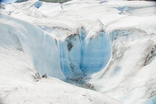 Water from surface streams cascade down a waterfall into the depths of the glacier.