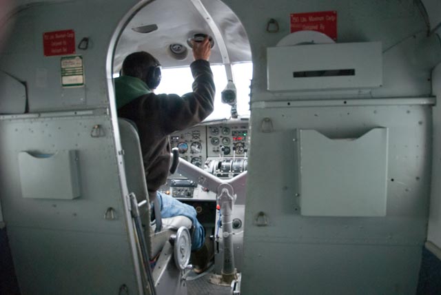 Brad, our pilot, tweaks some controls on the Otter. Marilyn called "shotgun" and got the prime seat next to the pilot. Dave and Tom were relegated to coach class.